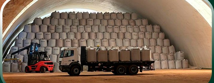 Caminhão e empilhadeira carregando big bags dentro de um galpão inflável