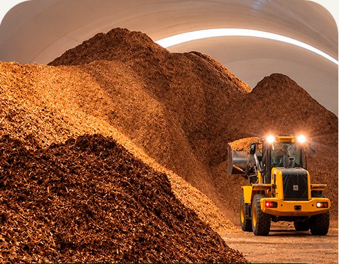 Pá carregadeira movimentando biomassa dentro de galpão inflável