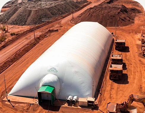 Galpão inflável em área de mineração com caminhões fora de estrada